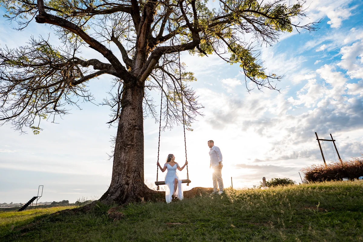 Ensaio do casal no balanço sob a árvore ao pôr do sol