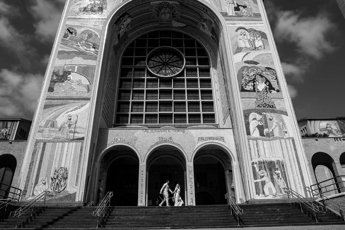 Casal de mãos dadas diante da Basílica de Aparecida