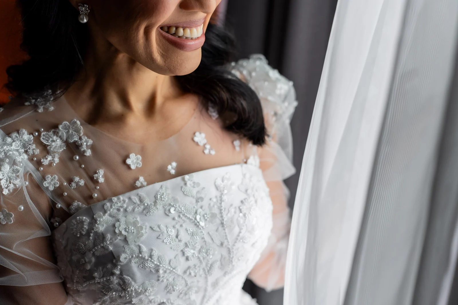 Detalhe do vestido bordado e sorriso da noiva